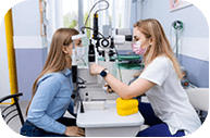 Doctor checking young boy's vision with clinical diagnostic equipment
